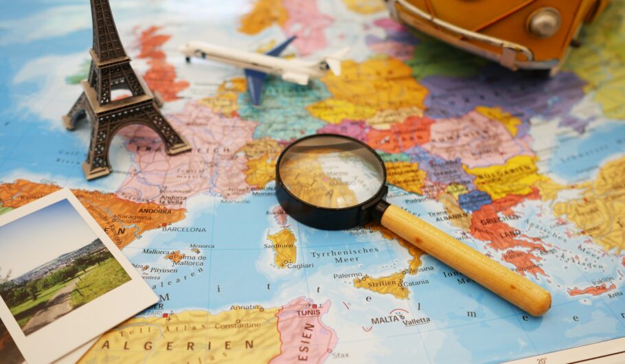 Weltkarte mit Europa-Ausschnitt, VW Bus, Eiffelturm und Reisefotos – Symbolbild für entspannte Urlaubsplanung