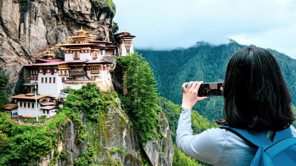 Das Tigernest-Kloster in Bhutan, spektakulär an einer steilen Felswand gelegen, umgeben von dichtem Wald und hoch aufragenden Bergen.