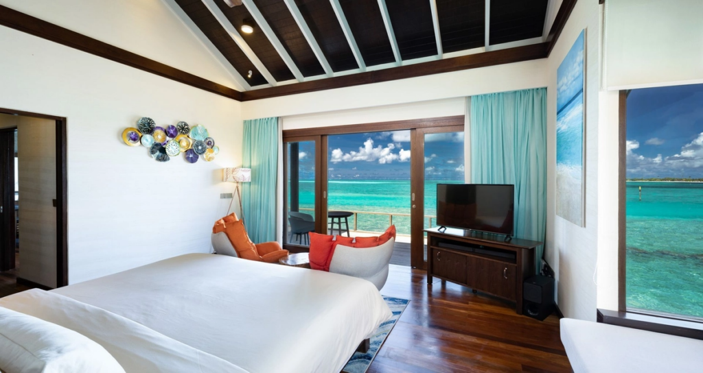 Hotelzimmer im Atmosphere Kanifushi Maldives mit direktem Blick auf den türkisblauen Ozean.