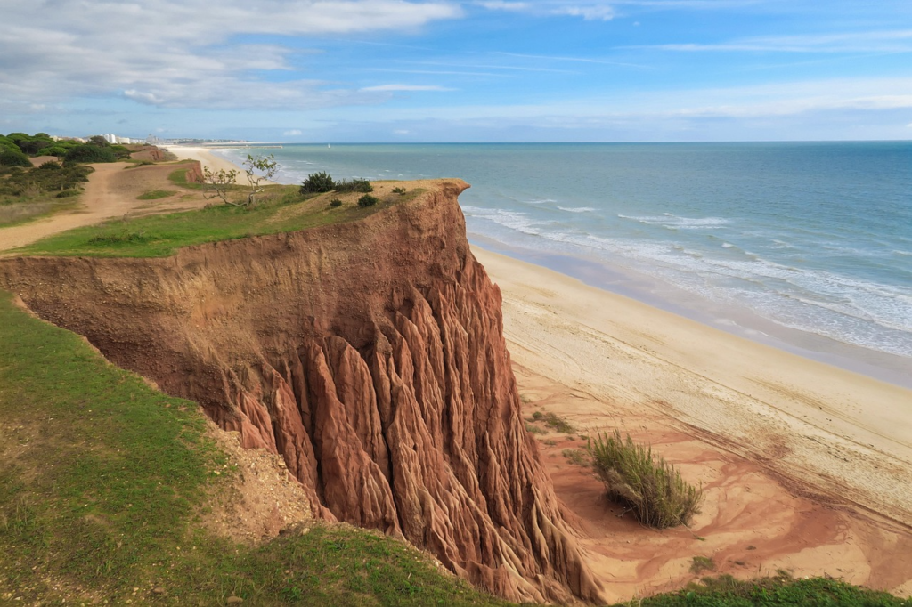 Küstenlandschaft der Praia da Falésia in Portugal mit markanten roten Felswänden und weitläufigem Strand